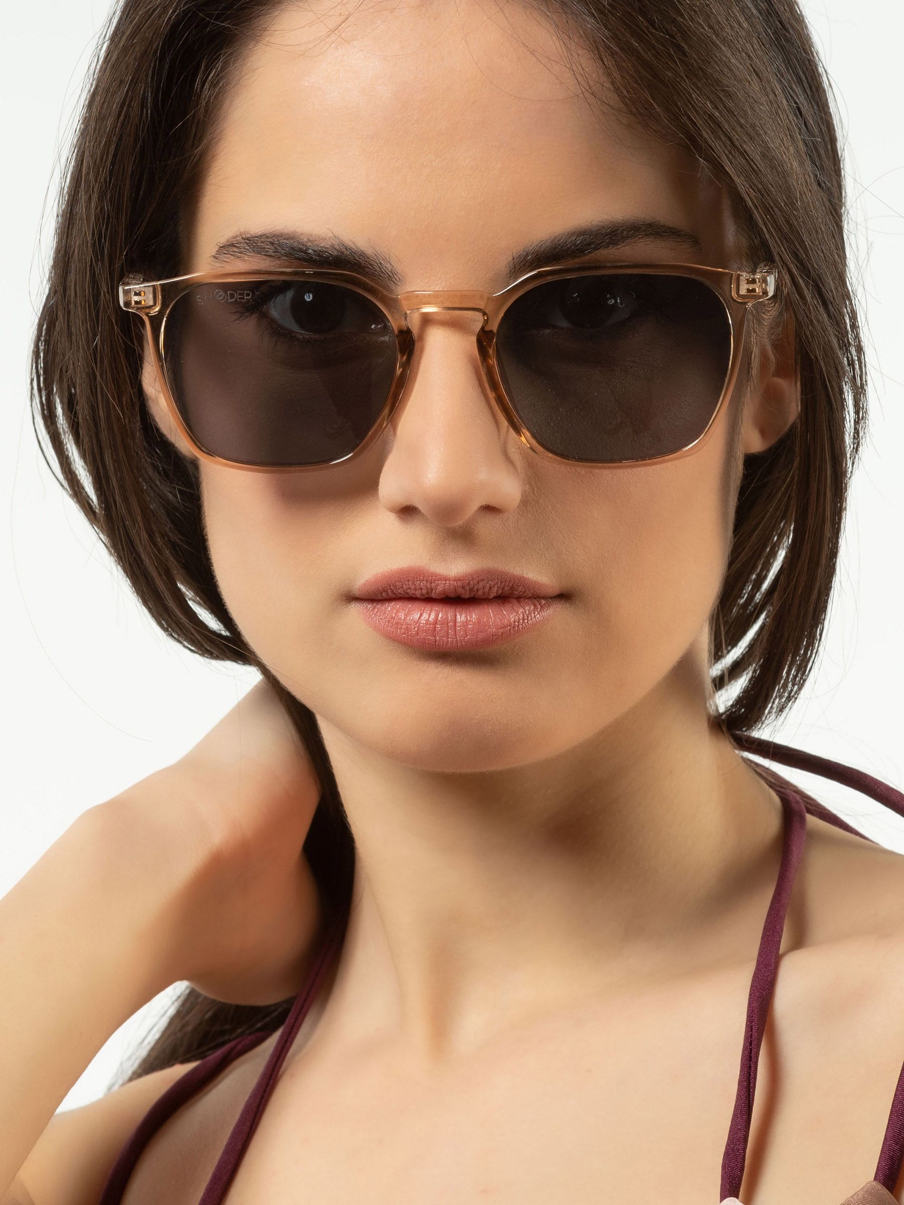 Donna con occhiali da sole con montatura marrone chiaro e lenti scure. Primo piano.