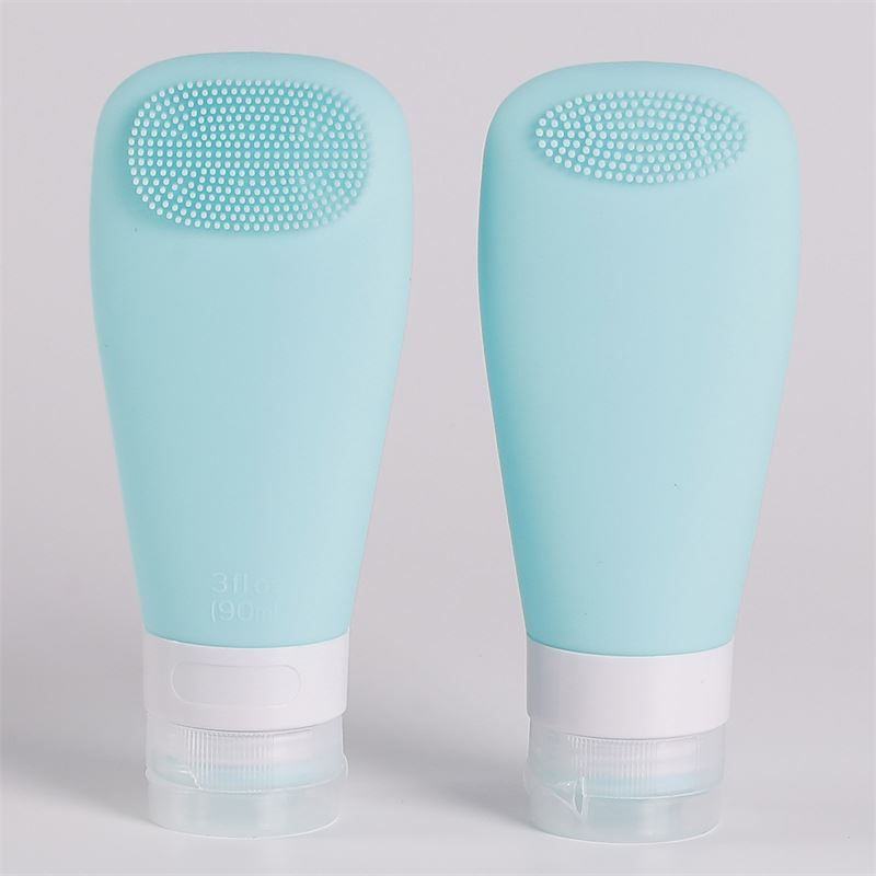 Due flaconi in silicone color acqua con spazzola integrata e tappo bianco.