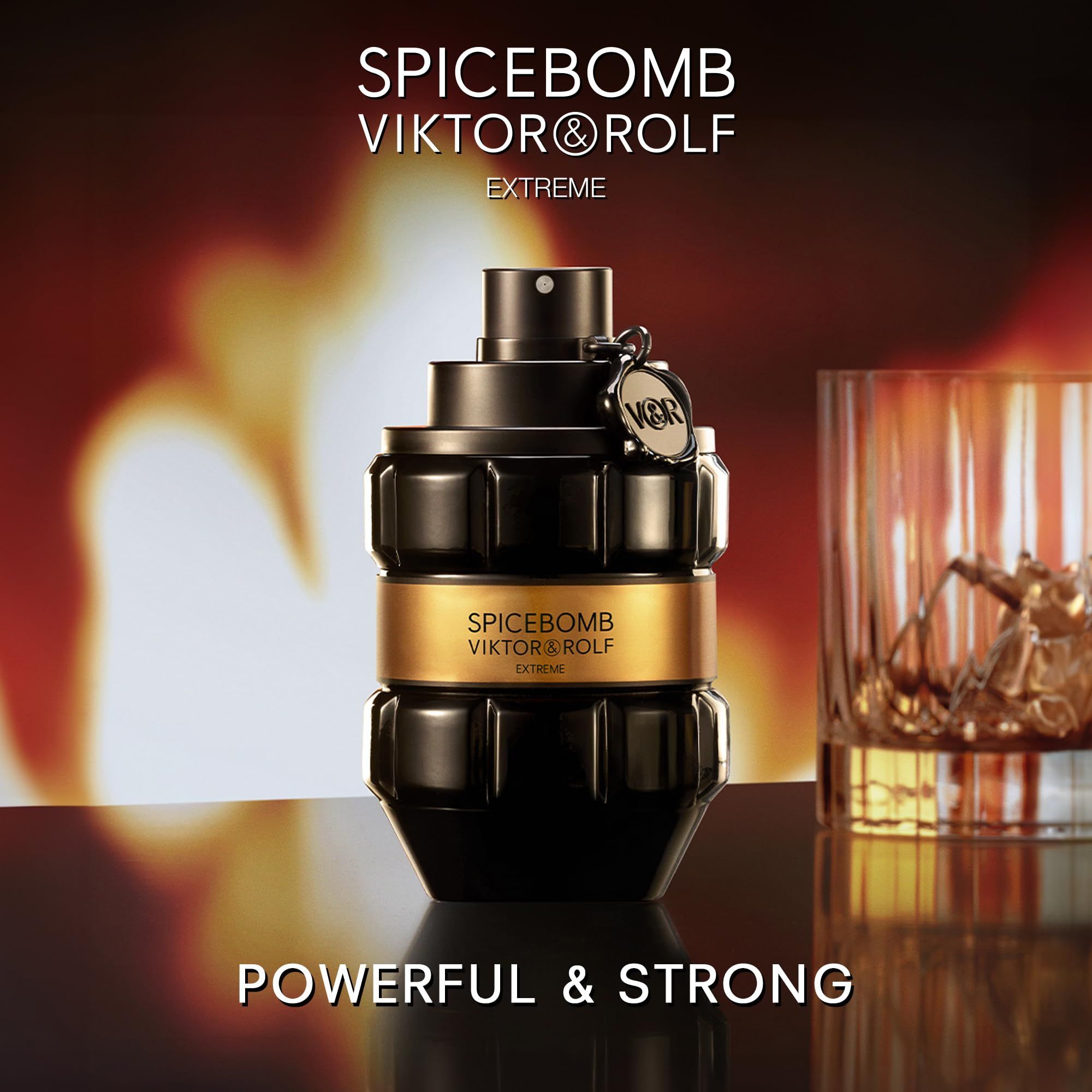 Flacone nero con fascia dorata. Scritta: SPICEBOMB VIKTOR&ROLF EXTREME. Bicchiere con liquido. Sfondo: fuoco.