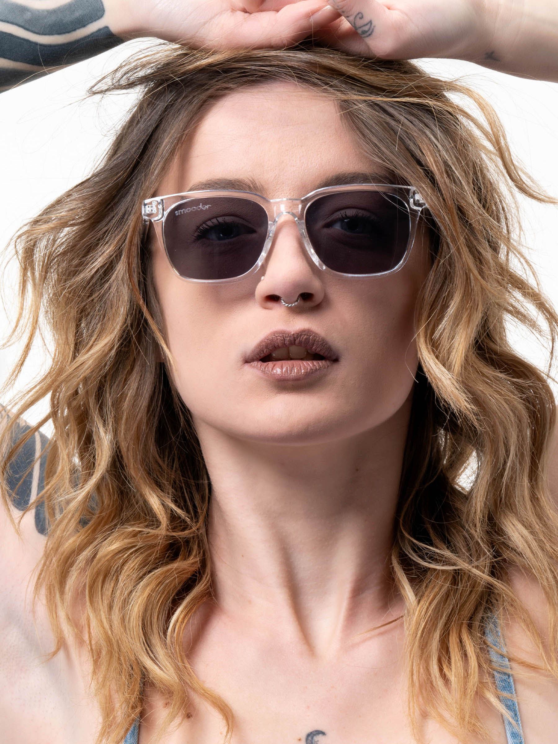 Donna con occhiali da sole trasparenti con lenti scure. Il logo Smooder è visibile.