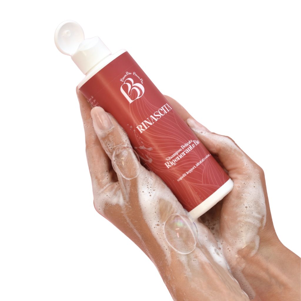 Mani che tengono un flacone. Schiuma sulle mani. Scritta RINASCITA e logo.