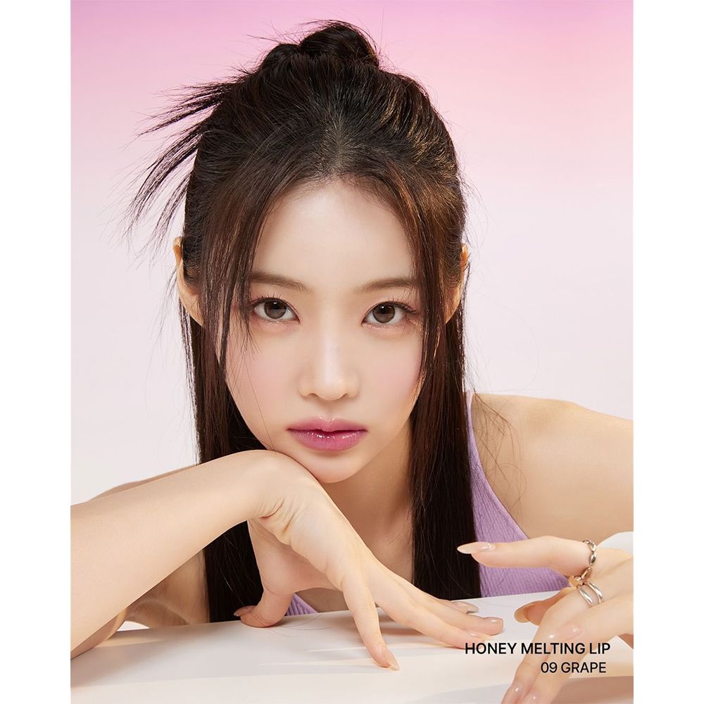 Ritratto di donna con Honey Melting Lip Gloss 09 Grape. Testo: HONEY MELTING LIP, 09 GRAPE.