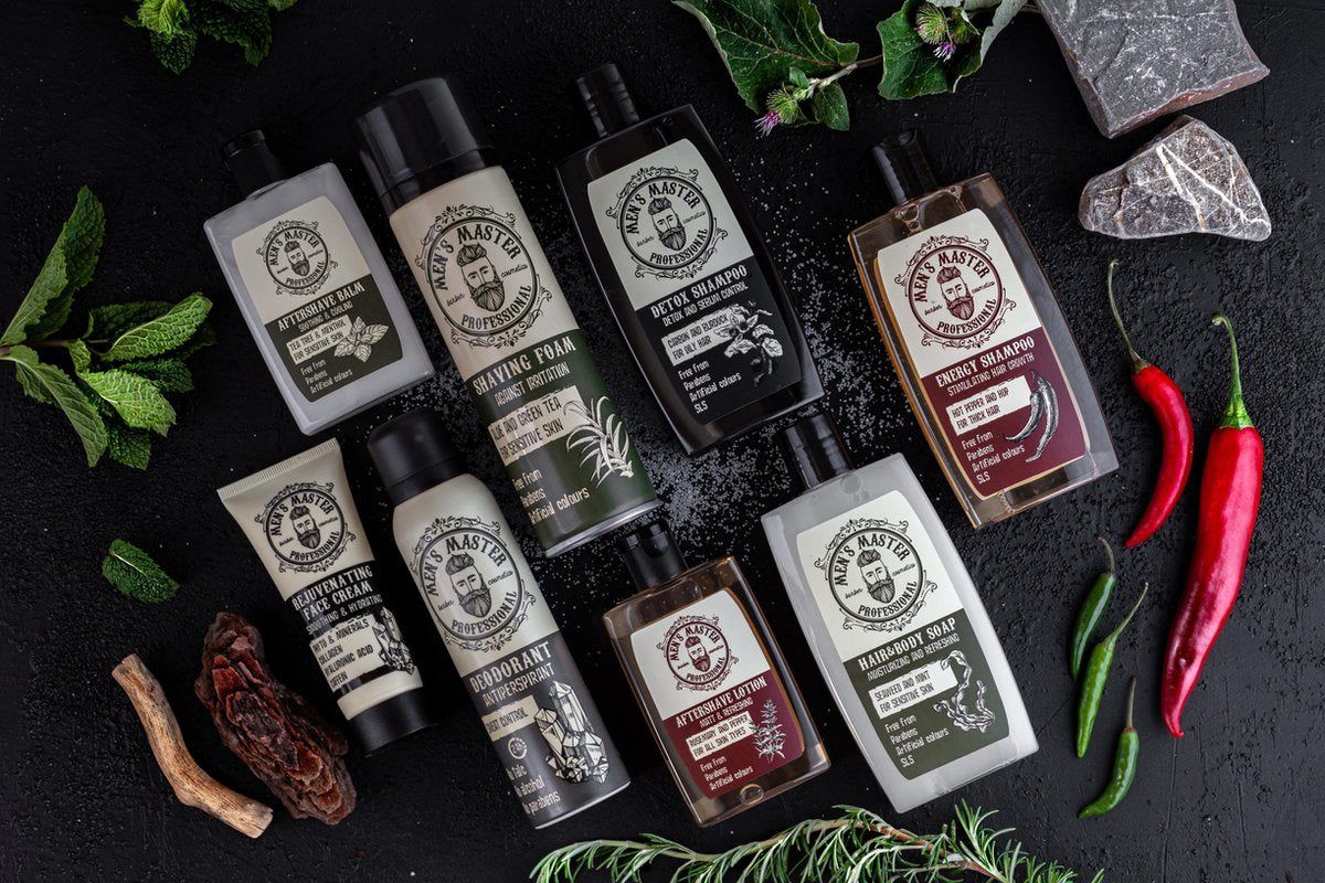 Disposizione di prodotti su sfondo scuro. Vari prodotti con logo e testo. Deodorante, crema da barba, shampoo, sapone, ecc. Con erbe.