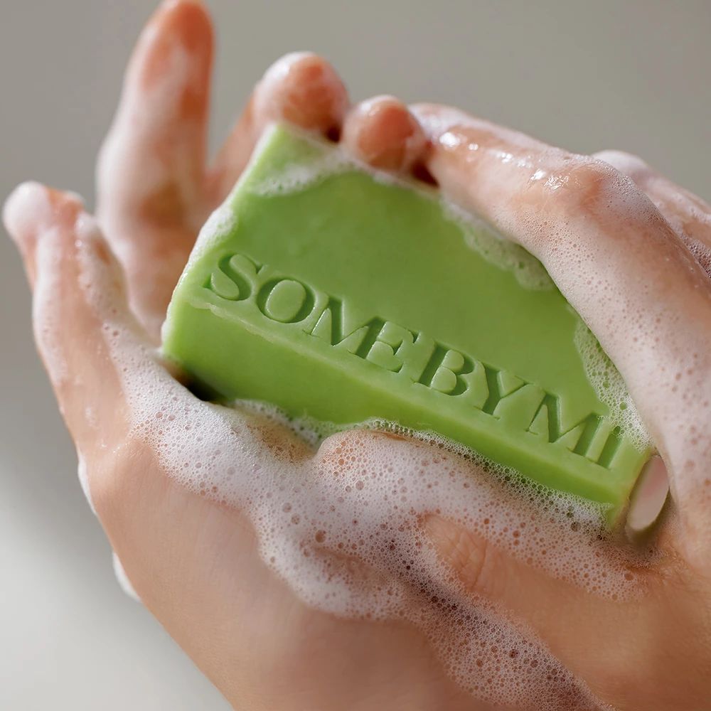 Mani lavate con un panetto di sapone verde con scritta 'SOMEBYMI'.