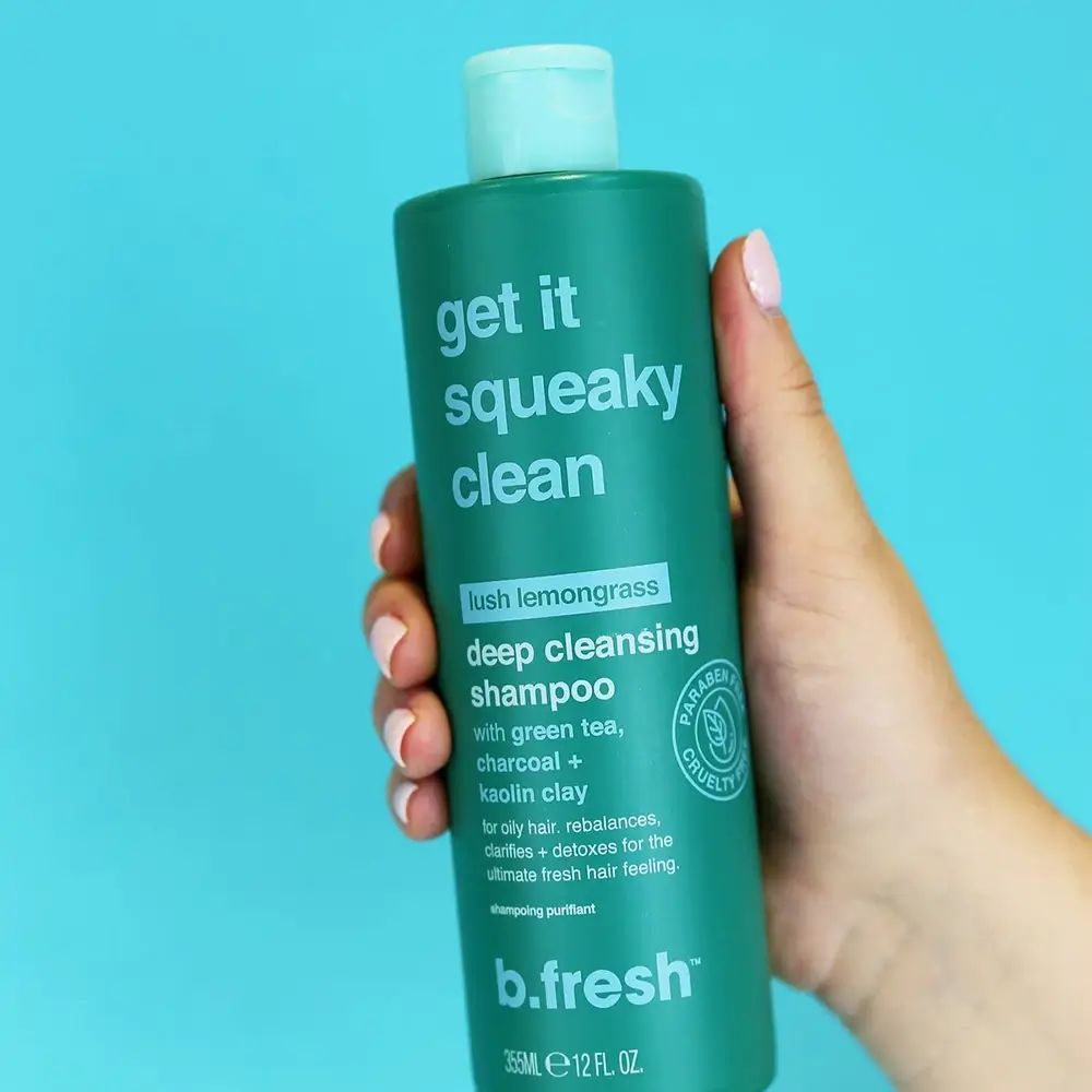 Flacone di shampoo verde con "Get it squeaky clean". Contiene tè verde, carbone e argilla di caolino. Marchio: B.fresh.