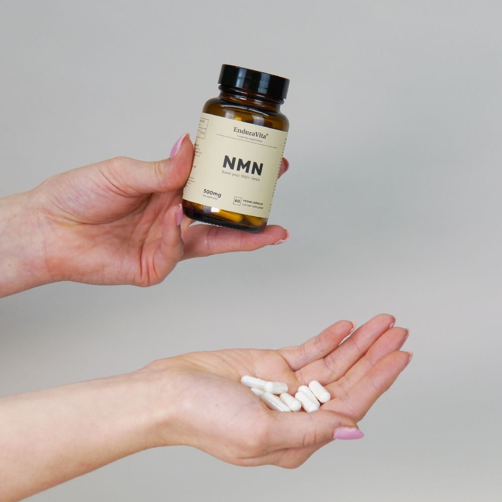 Mani che tengono una bottiglia marrone e capsule bianche. Scritta: EnduraVita, NMN, 500mg.