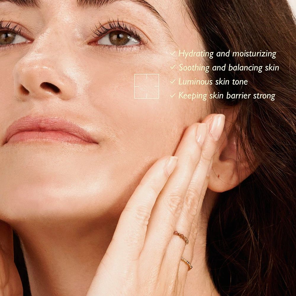 Primo piano di una donna che si tocca la pelle. Testo: Idratante, lenitivo, incarnato luminoso, barriera cutanea forte.