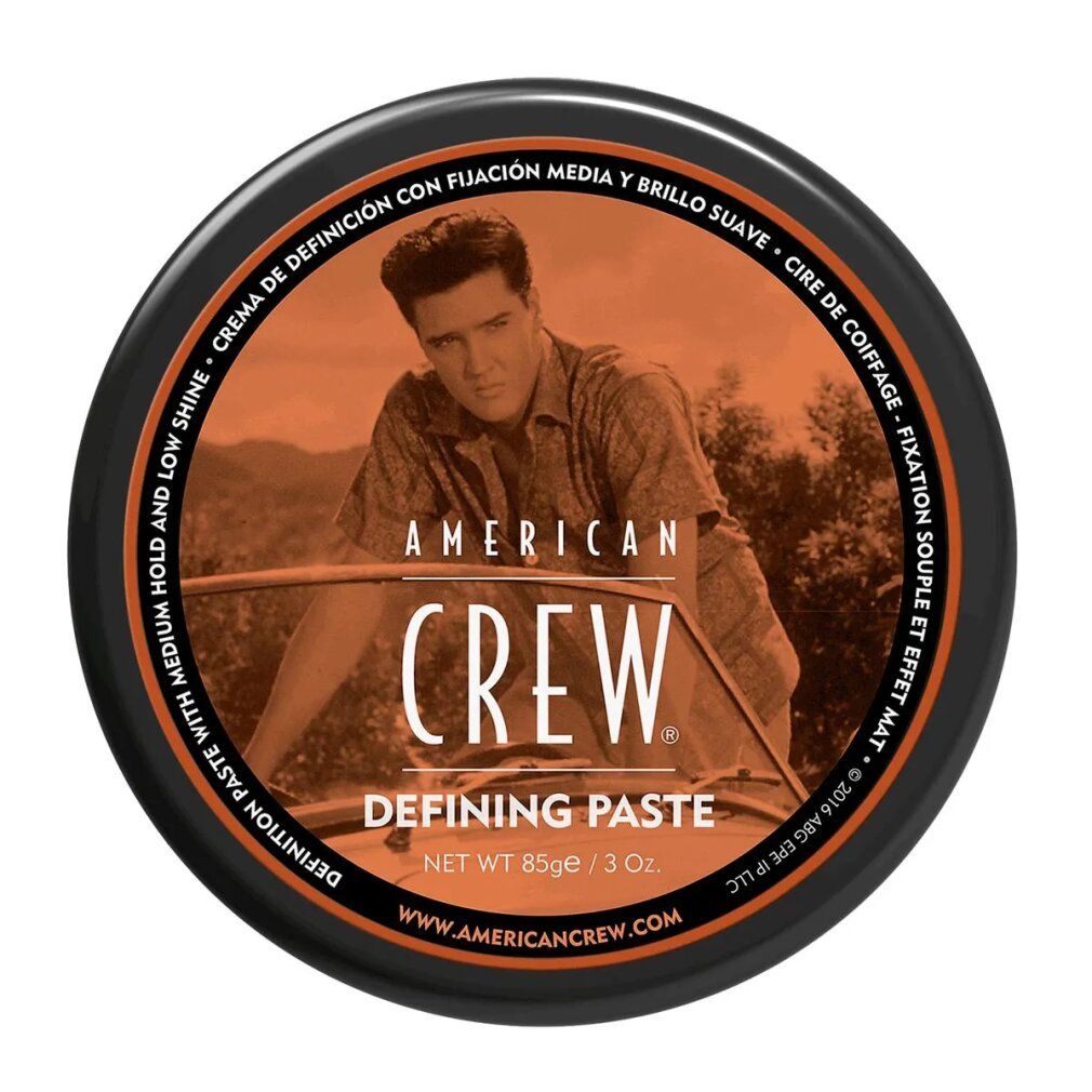 Barattolo rotondo nero con coperchio arancione. Testo: "American Crew Defining Paste". Contiene 85g/3oz.