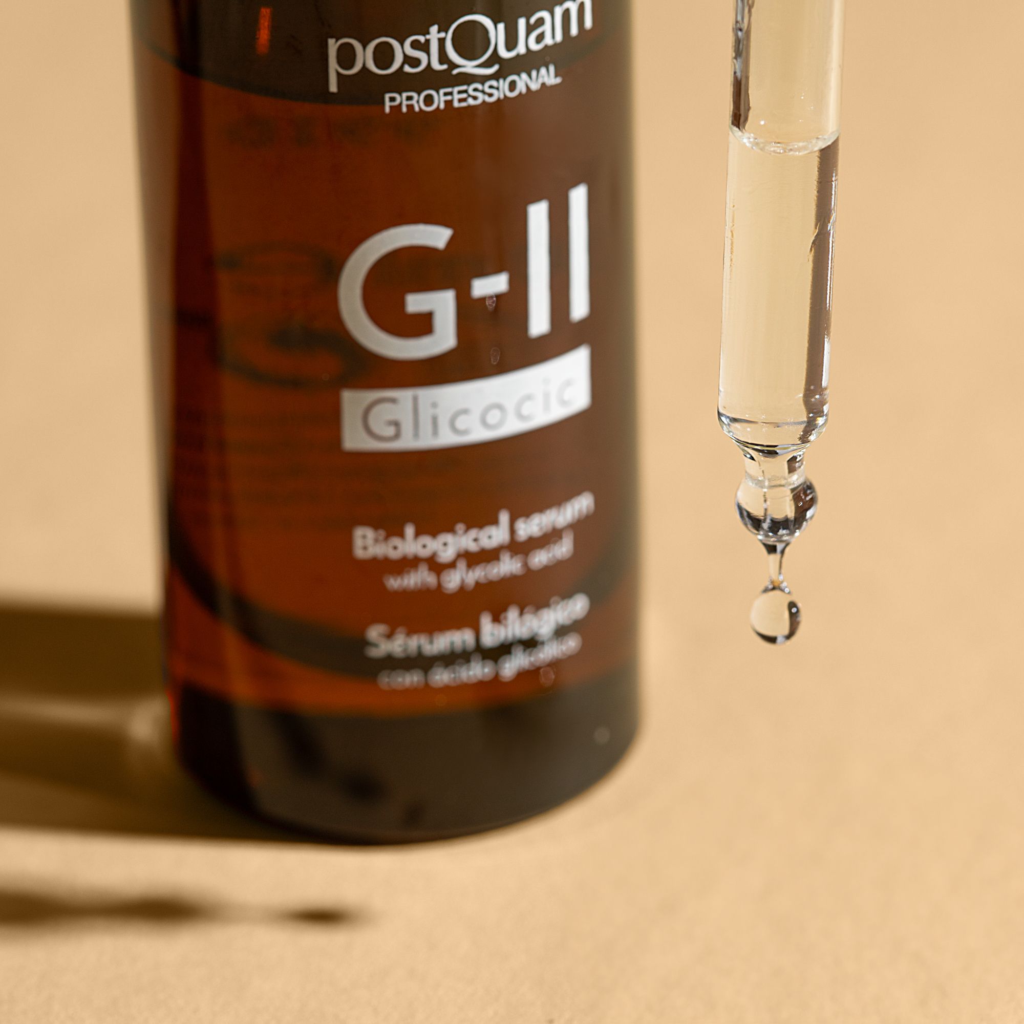 Primo piano di un flacone di siero con contagocce. Goccia di siero alla fine del contagocce. Scritta: PostQuam Professional, G-II Glicolic.