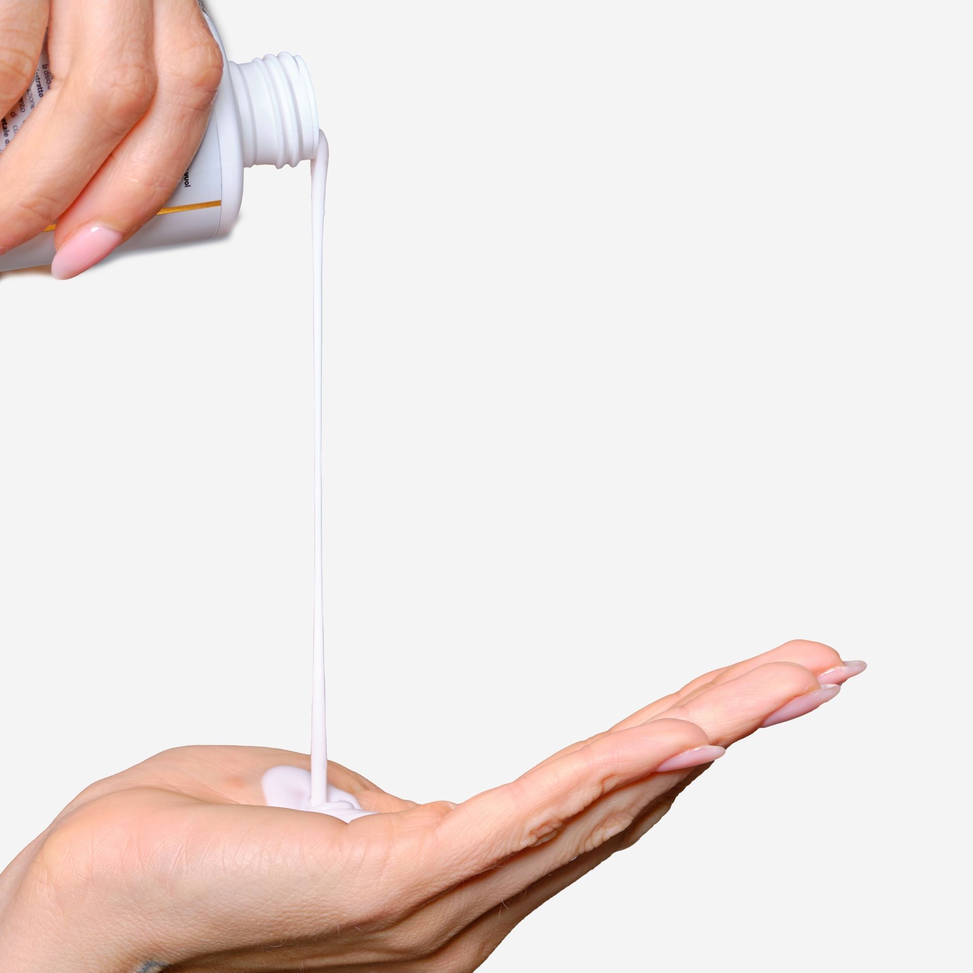 Mani che raccolgono liquido bianco da un flacone. Prodotto: Latte Struccante.