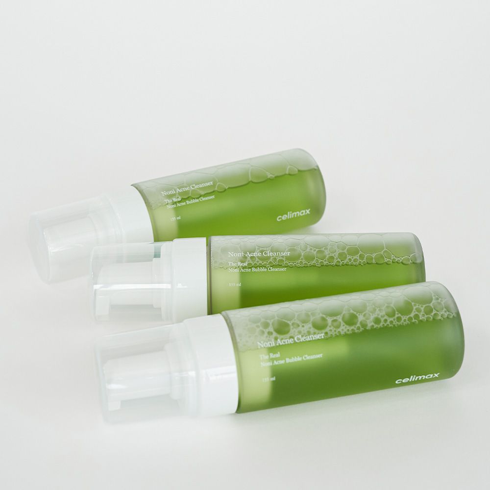 Tre flaconi di detergente schiumogeno anti-acne Celimax Noni uno accanto all'altro, con contenuto verde ed erogatori a pompa.