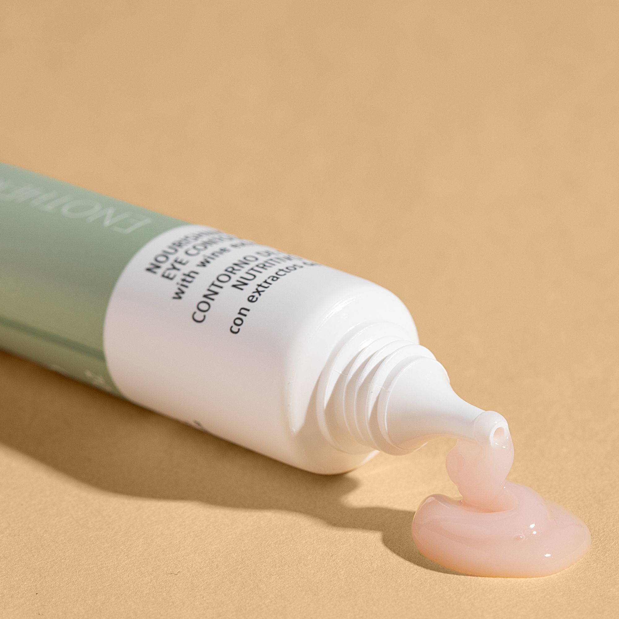 Tubo aperto, crema che esce. Testo: Crema contorno occhi nutriente. Sfondo: Beige.