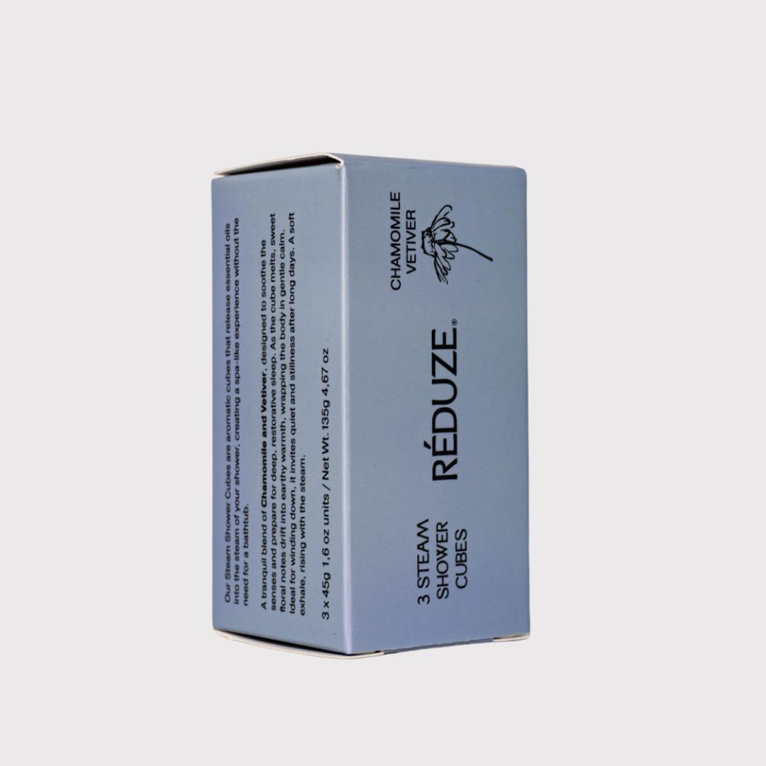 Una scatola blu con RÉDUZE, Camomilla & Vetiver e 3 Steam Shower Cubes. Forma quadrata.