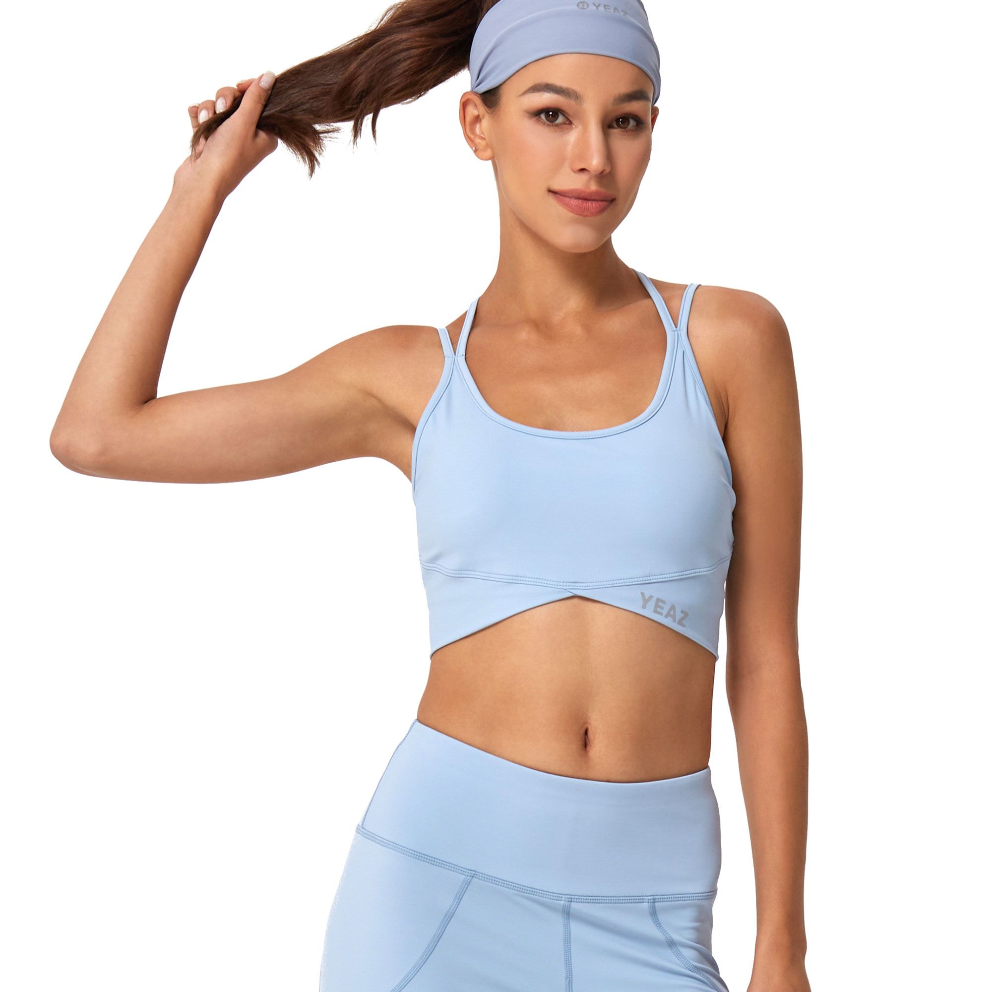 Brassiere sportiva azzurra con design incrociato e fascia coordinata. Marchio YEAX visibile.