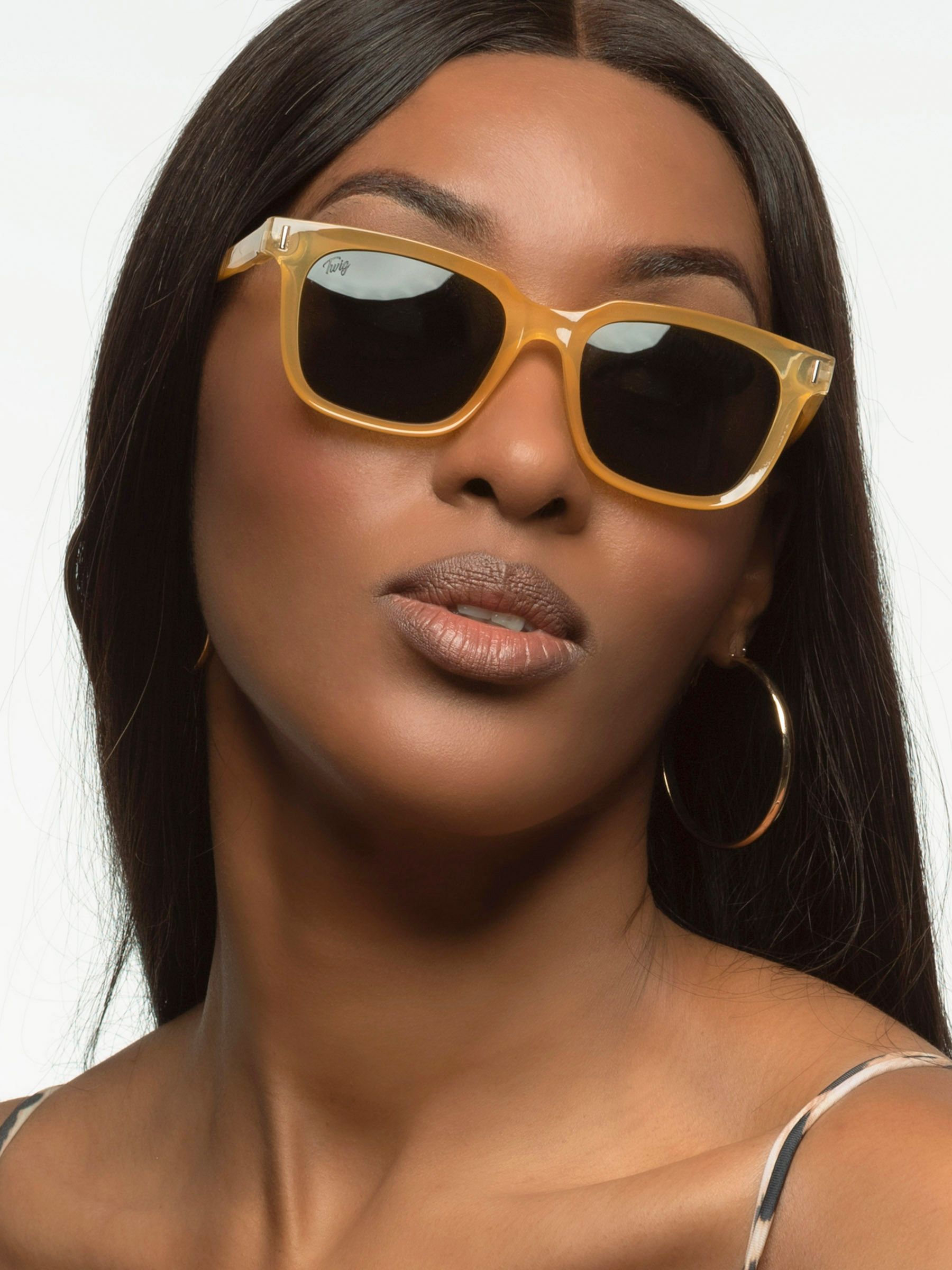 Donna con occhiali da sole gialli. Forma rettangolare, lenti scure. Primo piano.