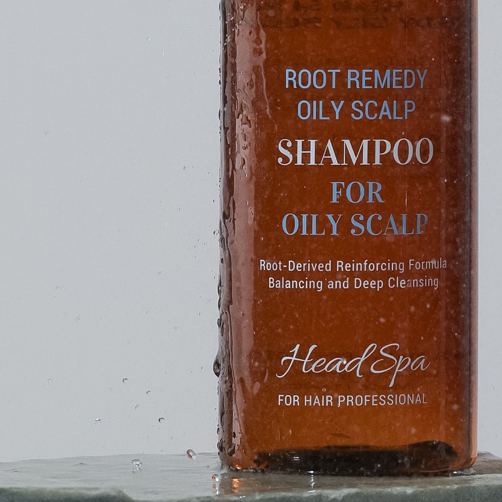 Primo piano del flacone di shampoo. Testo: Root Remedy Oily Scalp Shampoo for Oily Scalp, Head Spa.