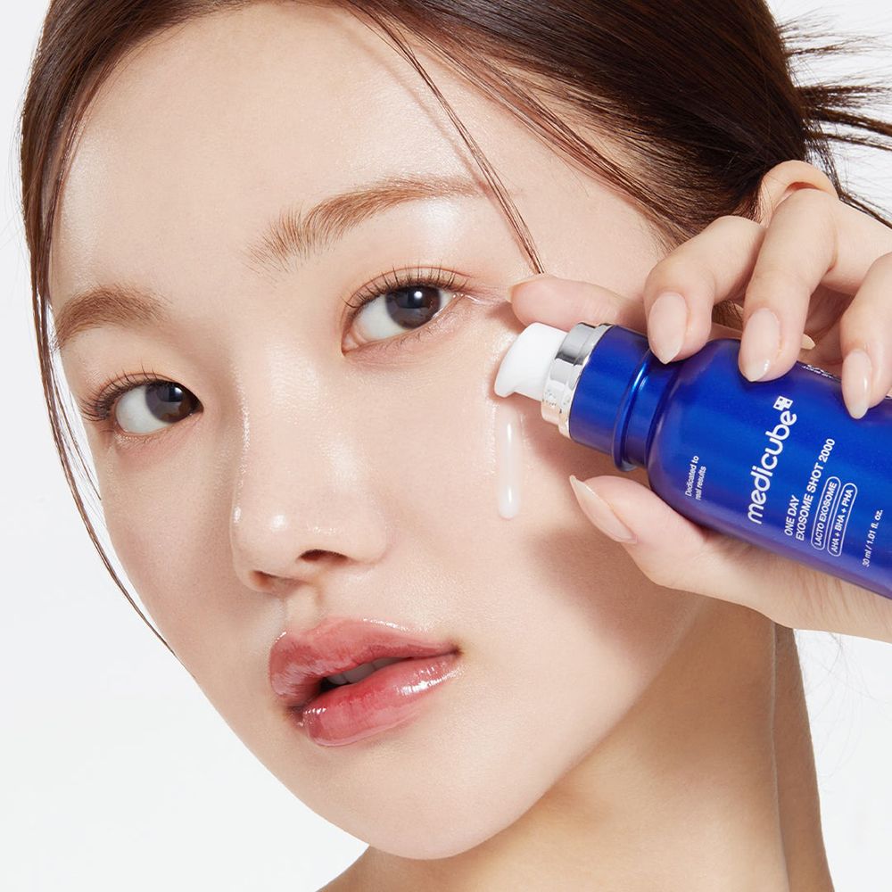 Donna applica il prodotto. Flacone blu con informazioni. Liquido che gocciola.