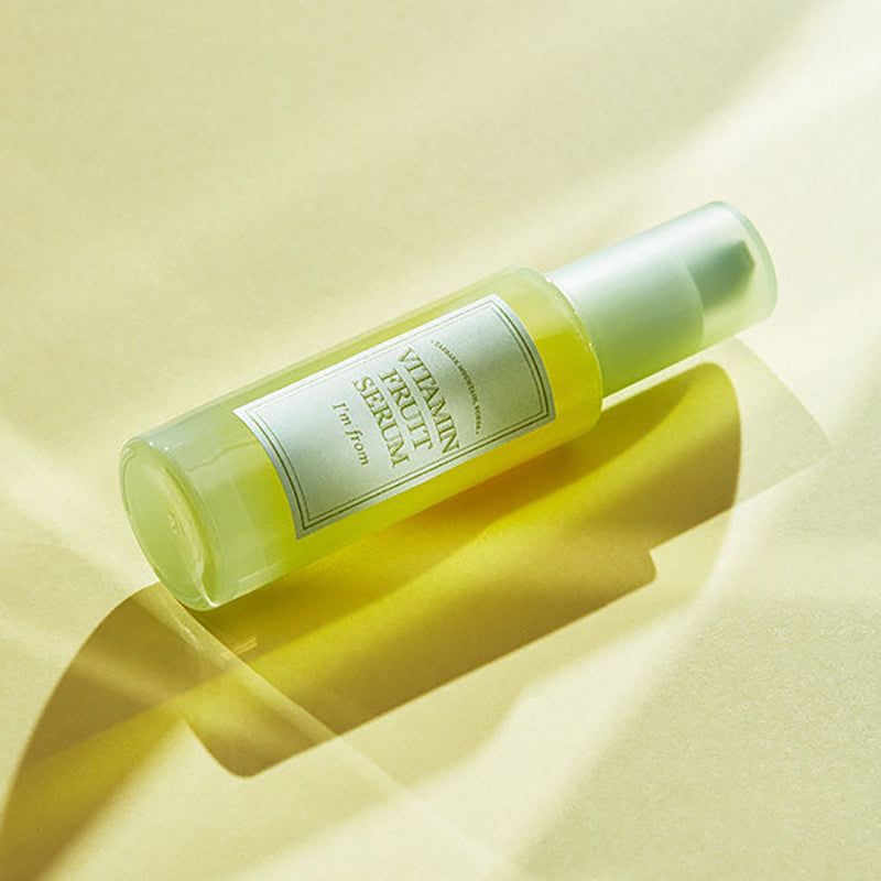 Flacone di siero su sfondo giallo. Scritta: Vitamin Fruit Serum, I'm from. Ombra.