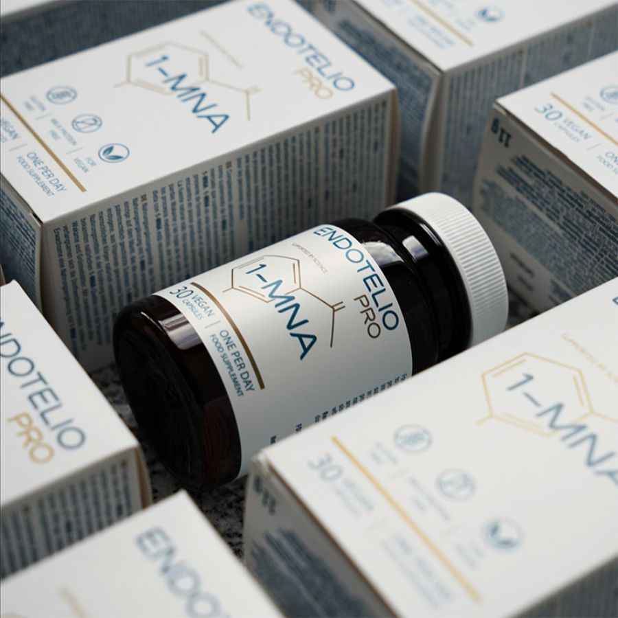 Flacone marrone di capsule circondato da scatole. Scritta: Endotelio PRO, 1-MNA, 30 capsule vegane. Confezione del prodotto.