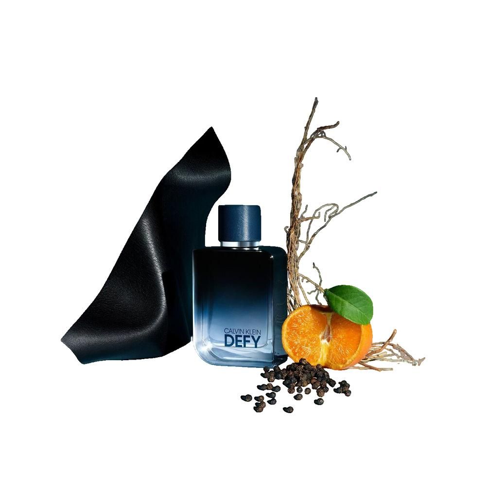 Flacone di profumo blu scuro con scritta DEF. Accanto a frutta, rami e nastro nero. Flacone con tappo blu.