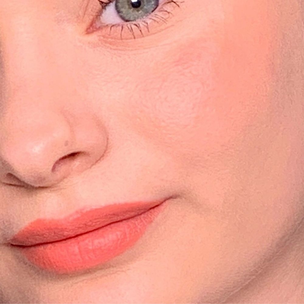 Primo piano di un viso. Labbra e guance con trucco rosa. Pelle chiara.