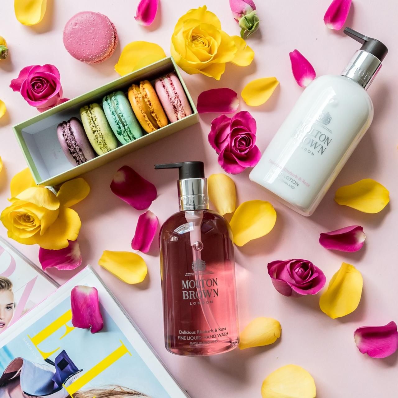 Due prodotti Molton Brown, macarons, rose e petali su sfondo rosa. Prodotti: lozione per le mani e sapone per le mani.