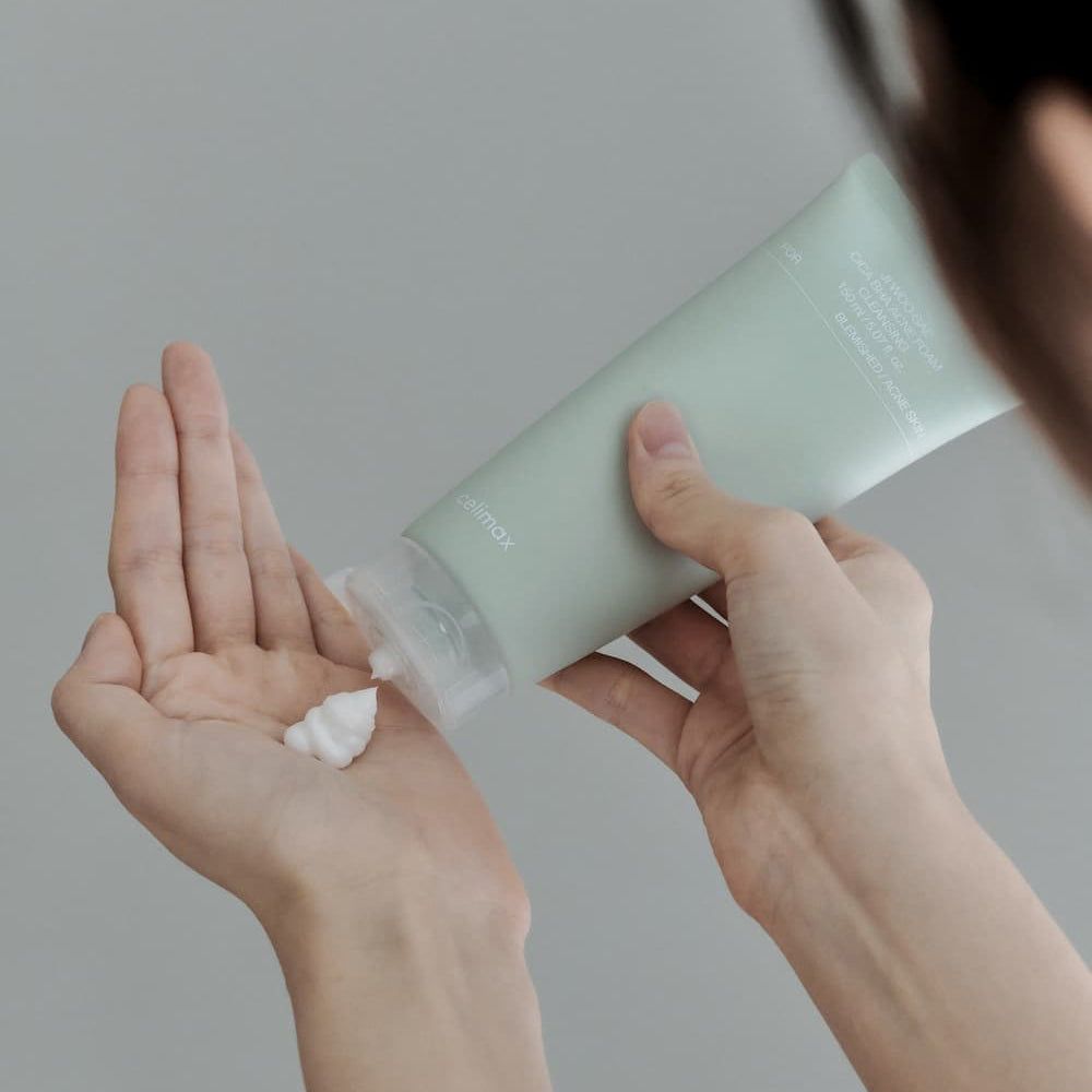 Una mano preme la schiuma detergente Cica BHA Celimax Ji Woo Gae nell'altra mano.