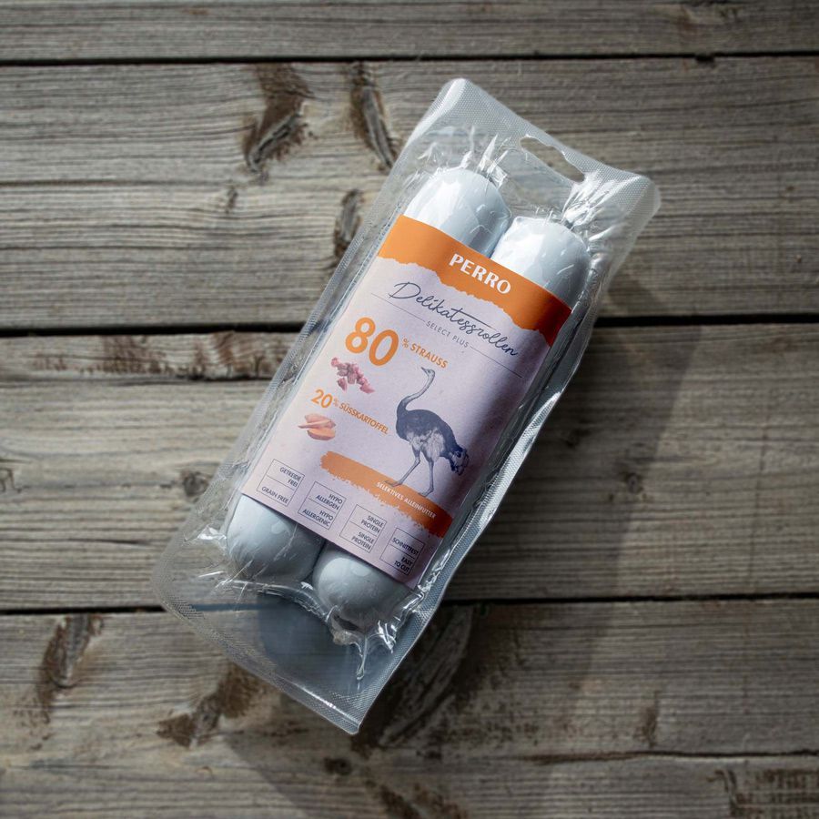 Confezione con due rotoli su fondo in legno. Stampa con struzzo, testo: PERRO Delikatessrollen, 80% struzzo, 20% patata dolce.