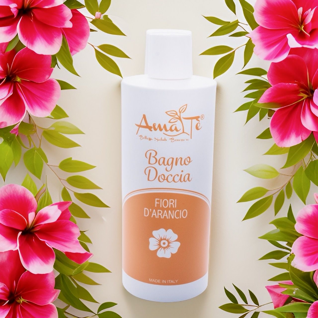 Flacone bianco con etichetta arancione. Testo: Bagnodoccia Fiori d'Arancio. Marchio: Amatè. Circondato da fiori rosa e foglie.