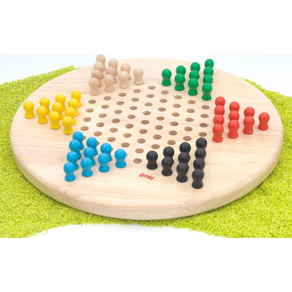 Tavola da gioco rotonda in legno con fori e pedine colorate. Pedine gialle, blu, verdi, rosse, nere e naturali disposte.
