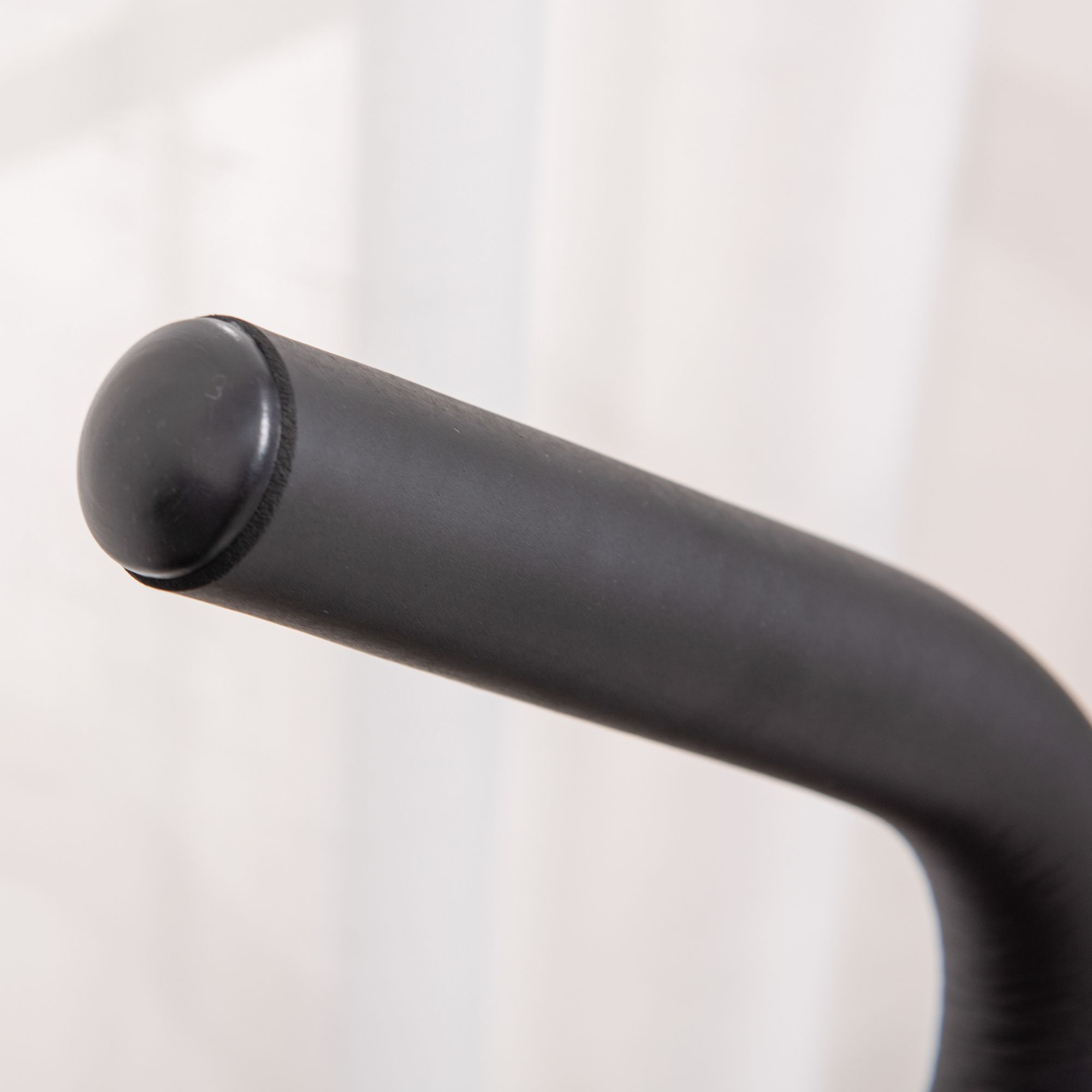 Primo piano dell'impugnatura nera di uno stepper. Forma rotonda, superficie liscia.