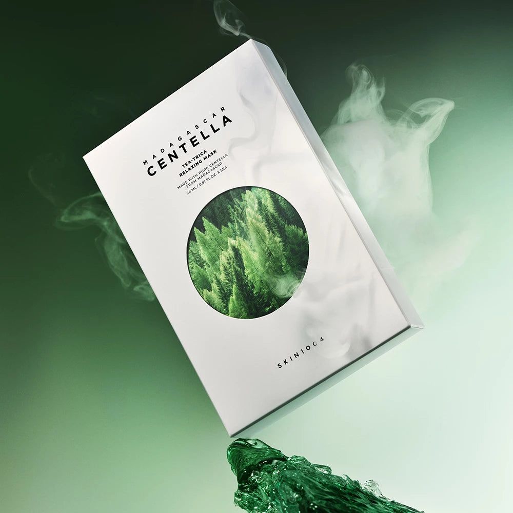 Scatola con nome del prodotto e motivo forestale, circondata da vapore e liquido verde. Testo: Madagascar Centella, Tea-Trica Relaxing Mask, SKIN1004.