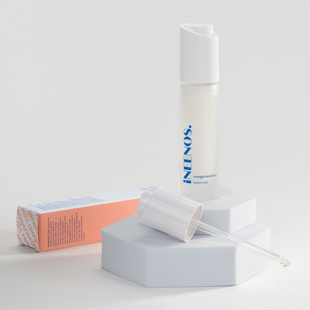 Siero unificante e idratante iNEENOS. con acido ialuronico. Il prodotto è in un flacone bianco con una pompa bianca e una scatola abbinata. La scatola riporta il nome del marchio e le informazioni sul prodotto in blu e pesca.