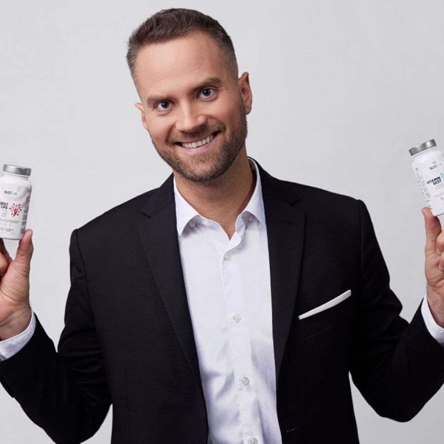 Un uomo tiene in mano due flaconi. Sui flaconi: BESTLAB, VITAMIN BEST. L'uomo sorride alla fotocamera.