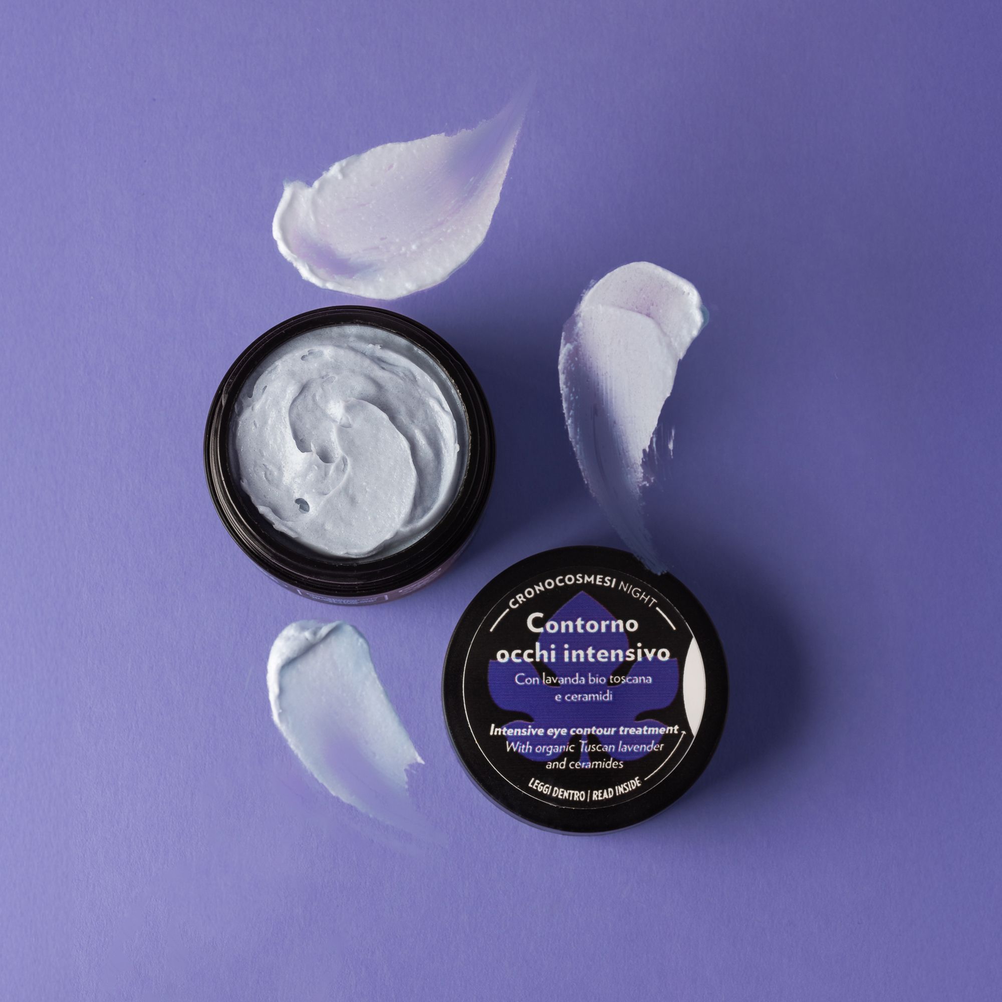 Vaso nero aperto con sostanza cremosa e tre macchie di crema. Sul coperchio, "Contorno occhi intensivo".