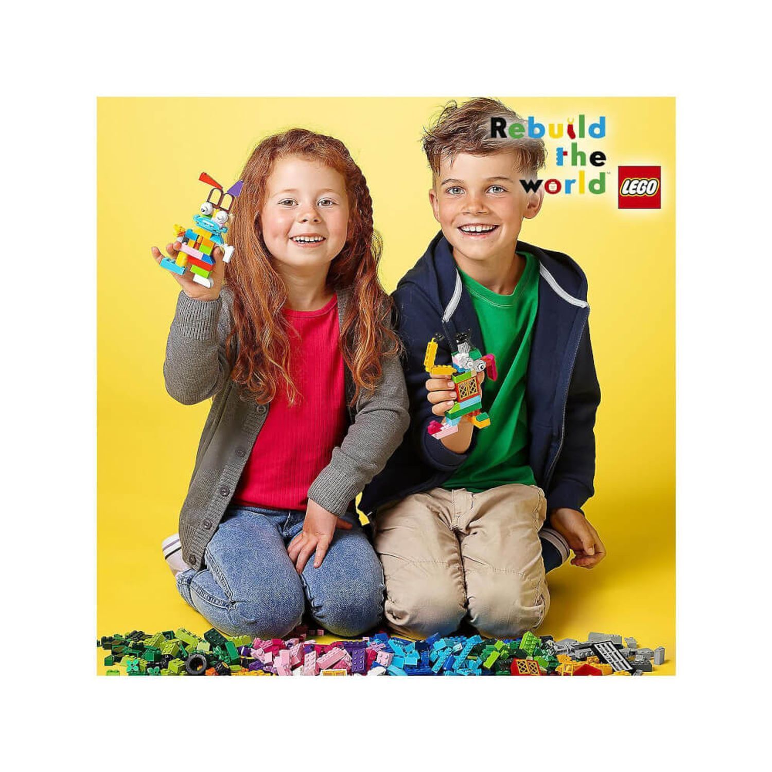 Due bambini tengono modelli LEGO. Mattoncini LEGO a terra. Scritta: Rebuild the world. Logo LEGO.