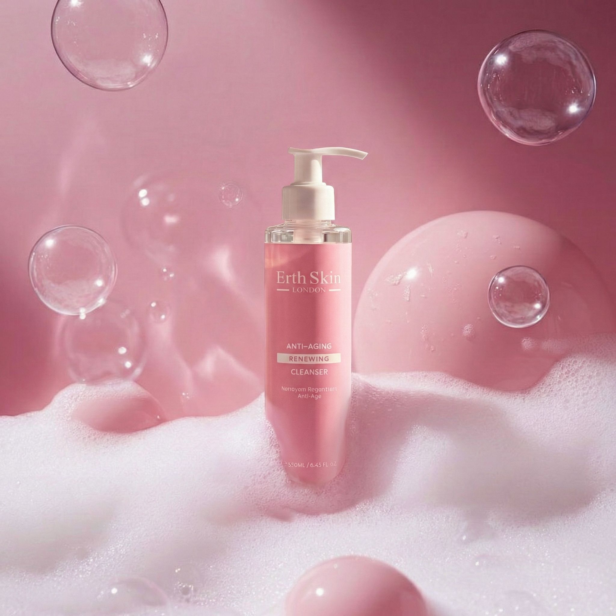 Flacone rosa con dosatore bianco. Scritta: Erth Skin London, Anti-Aging Renewing Cleanser. Circondato da bolle di sapone e schiuma.