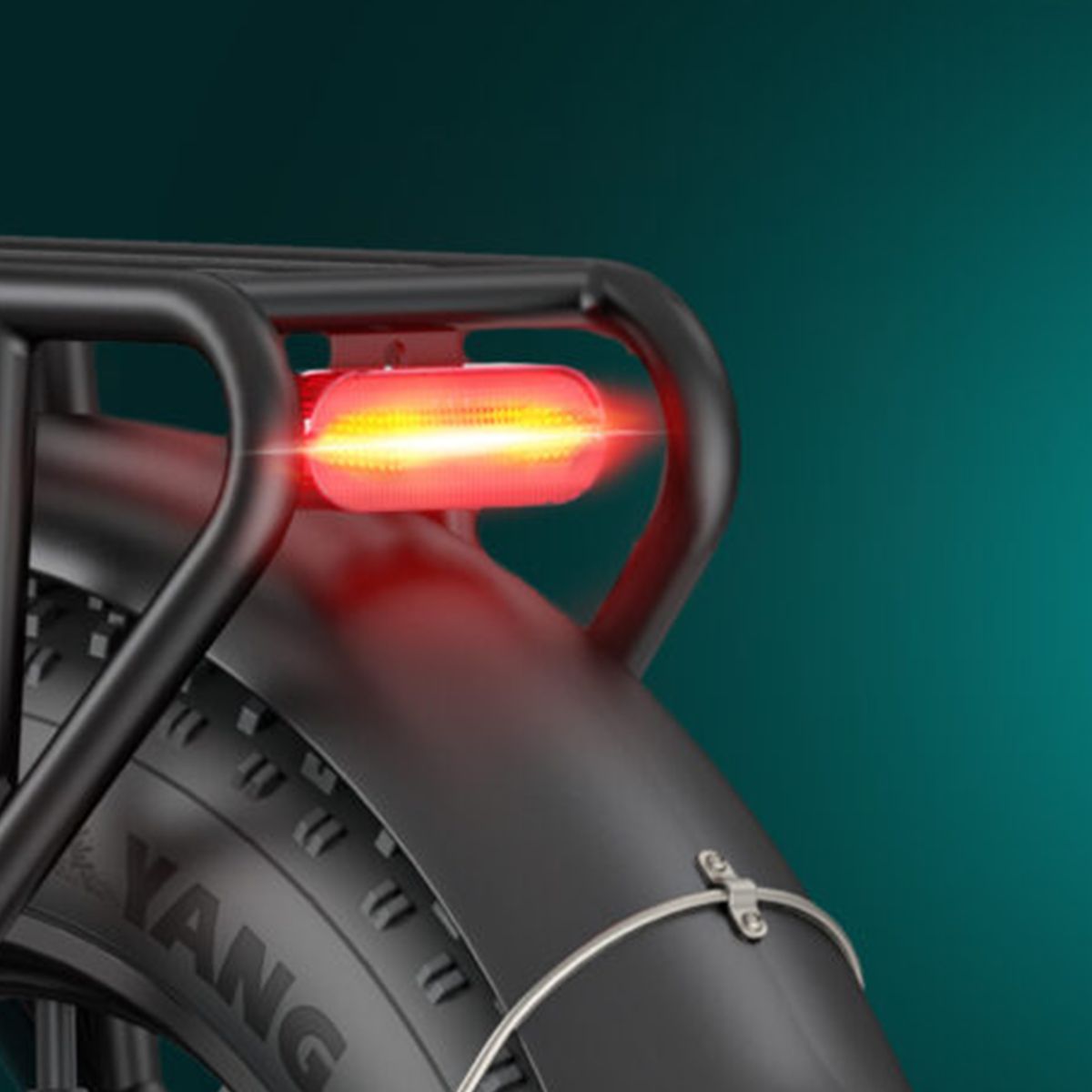 Fanale posteriore di una bicicletta nera. Luce rossa, montata su portapacchi. Pneumatico nero con scritta.