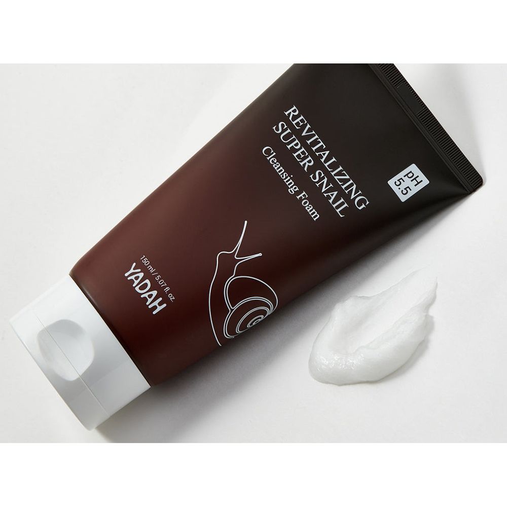 Tubo marrone con tappo bianco. Scritta: Revitalizing Super Snail Cleansing Foam. Accanto, una noce di schiuma detergente.