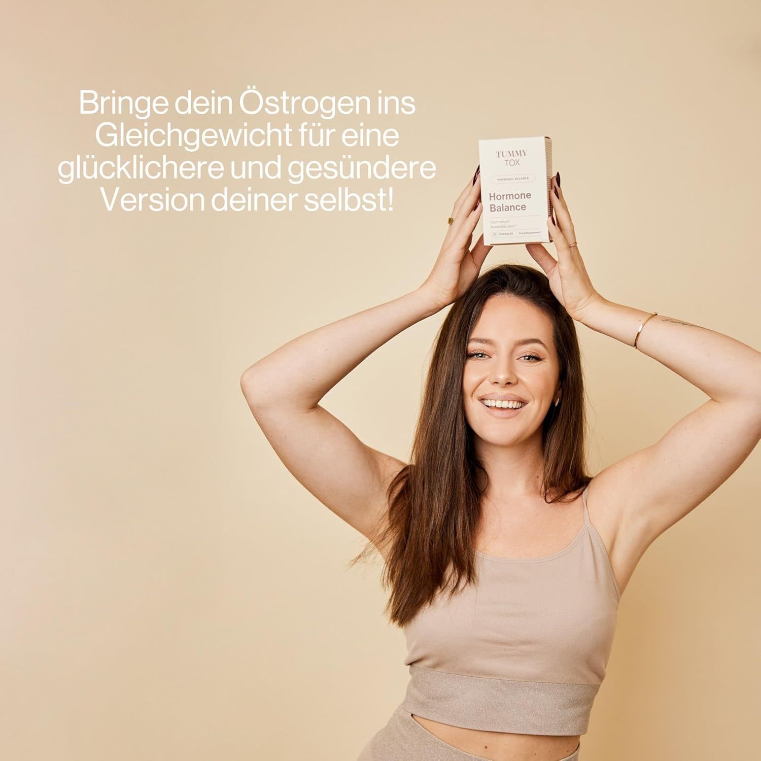 Donna tiene una scatola "Tummy Tox Hormone Balance" sopra la testa.