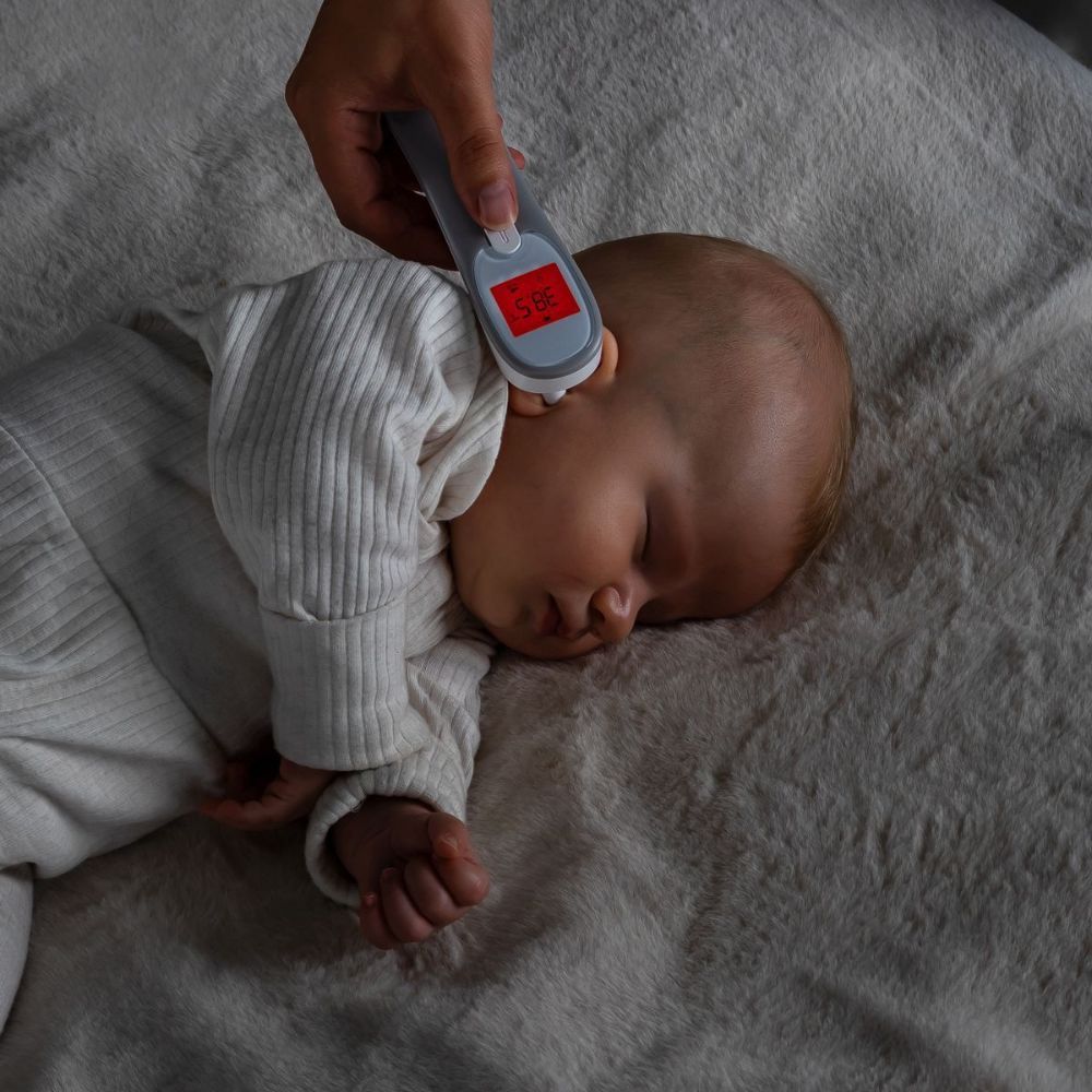 Termometro auricolare sull'orecchio di un bambino. Display con temperatura rossa.