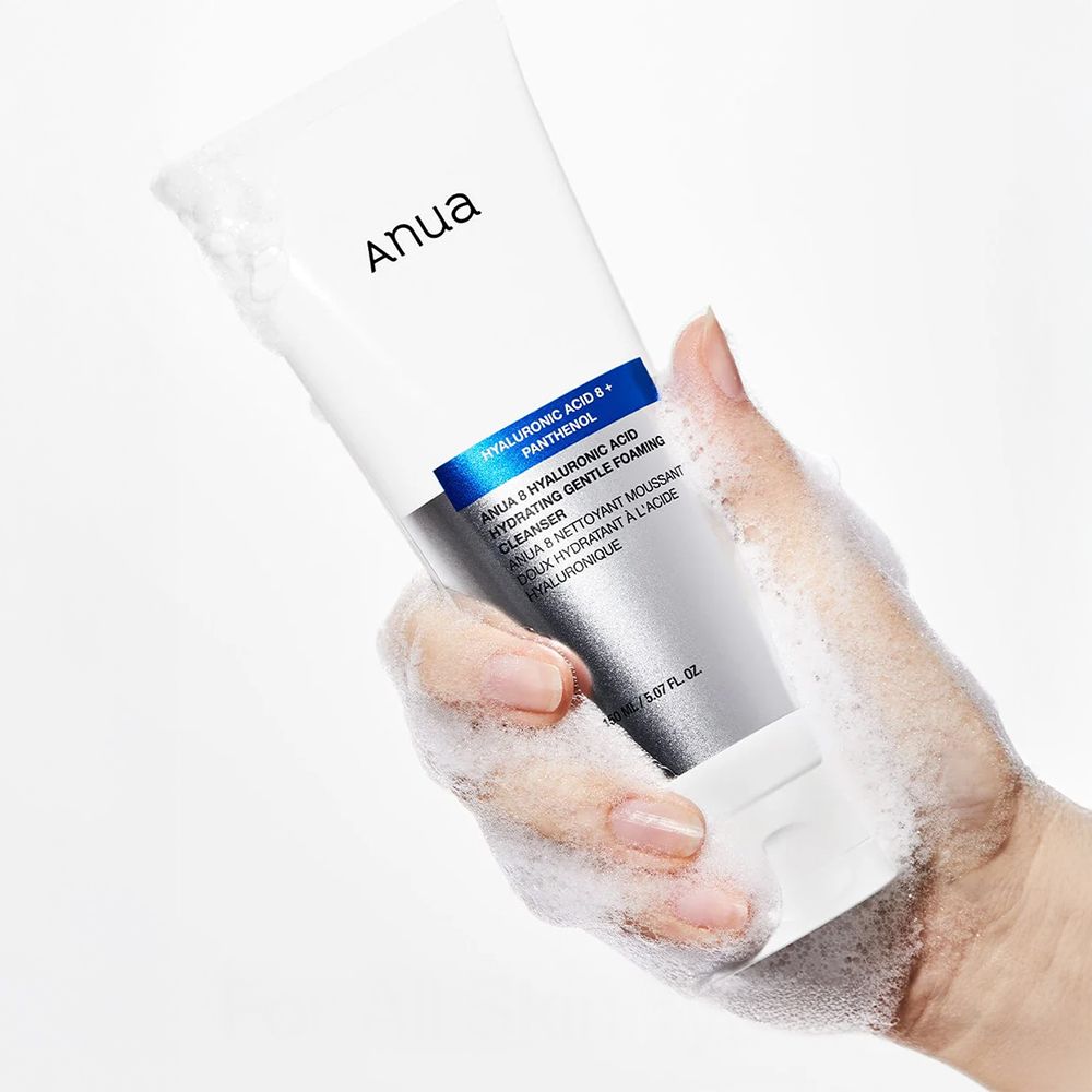Mano che tiene un tubo ANUA, circondato da schiuma detergente.