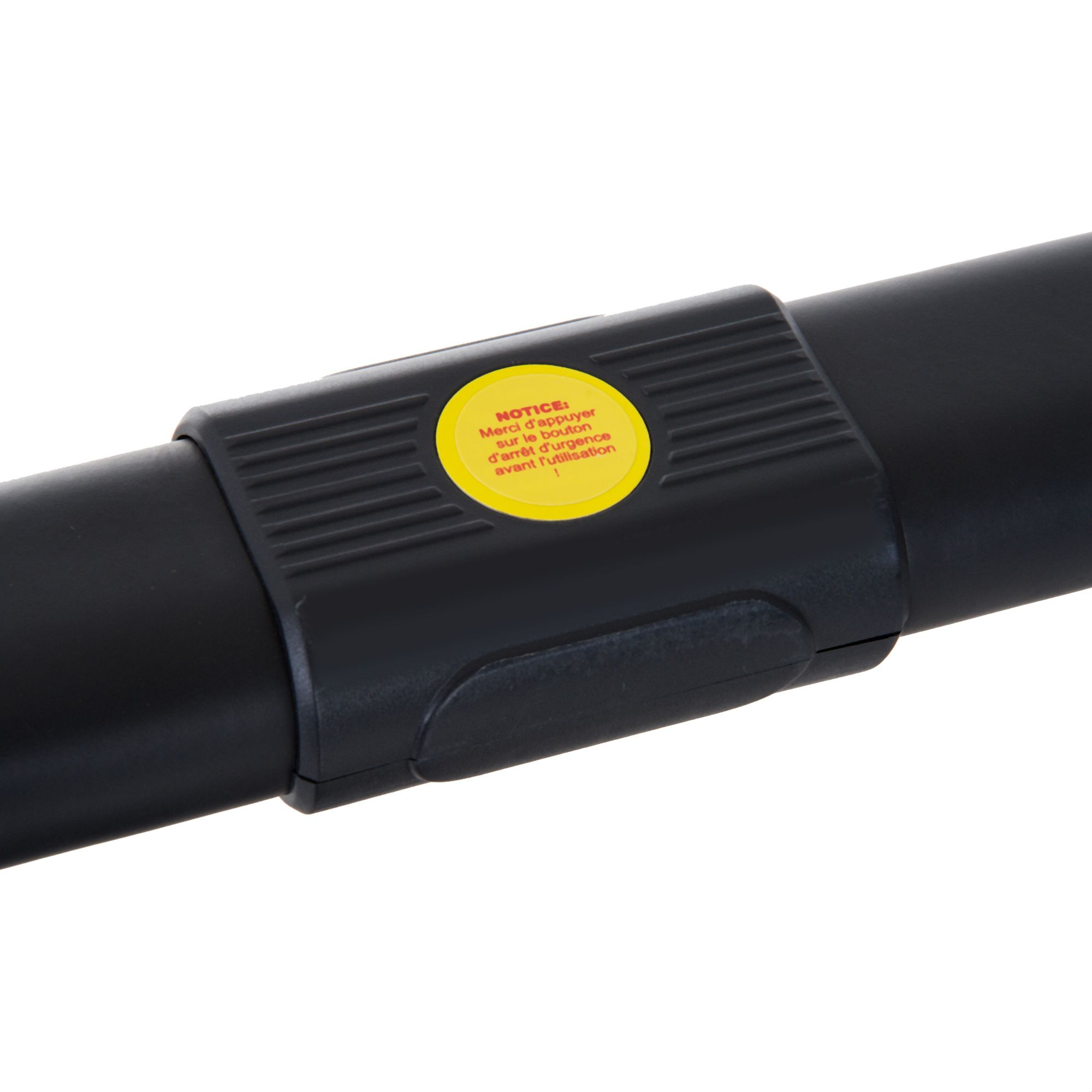 Primo piano di un giunto nero sul tapis roulant. Adesivo giallo con testo: 'NOTICE: Ne pas appuyer...'.