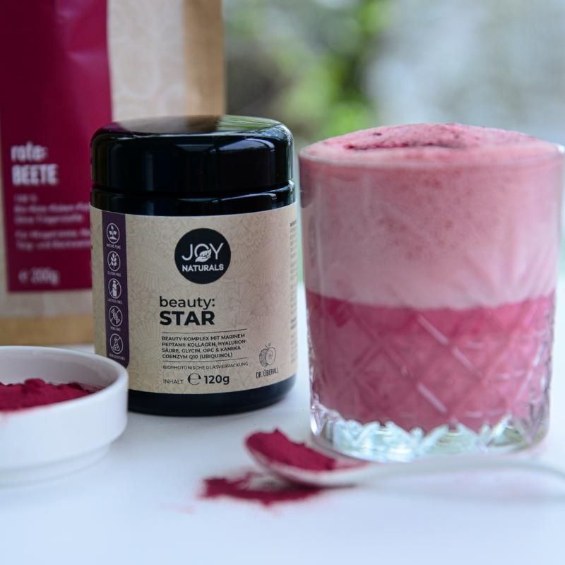 Barattolo scuro con coperchio, accanto a bicchiere con bevanda rosa. Etichetta con logo e nome beauty:STAR. Polvere e cucchiaio accanto.