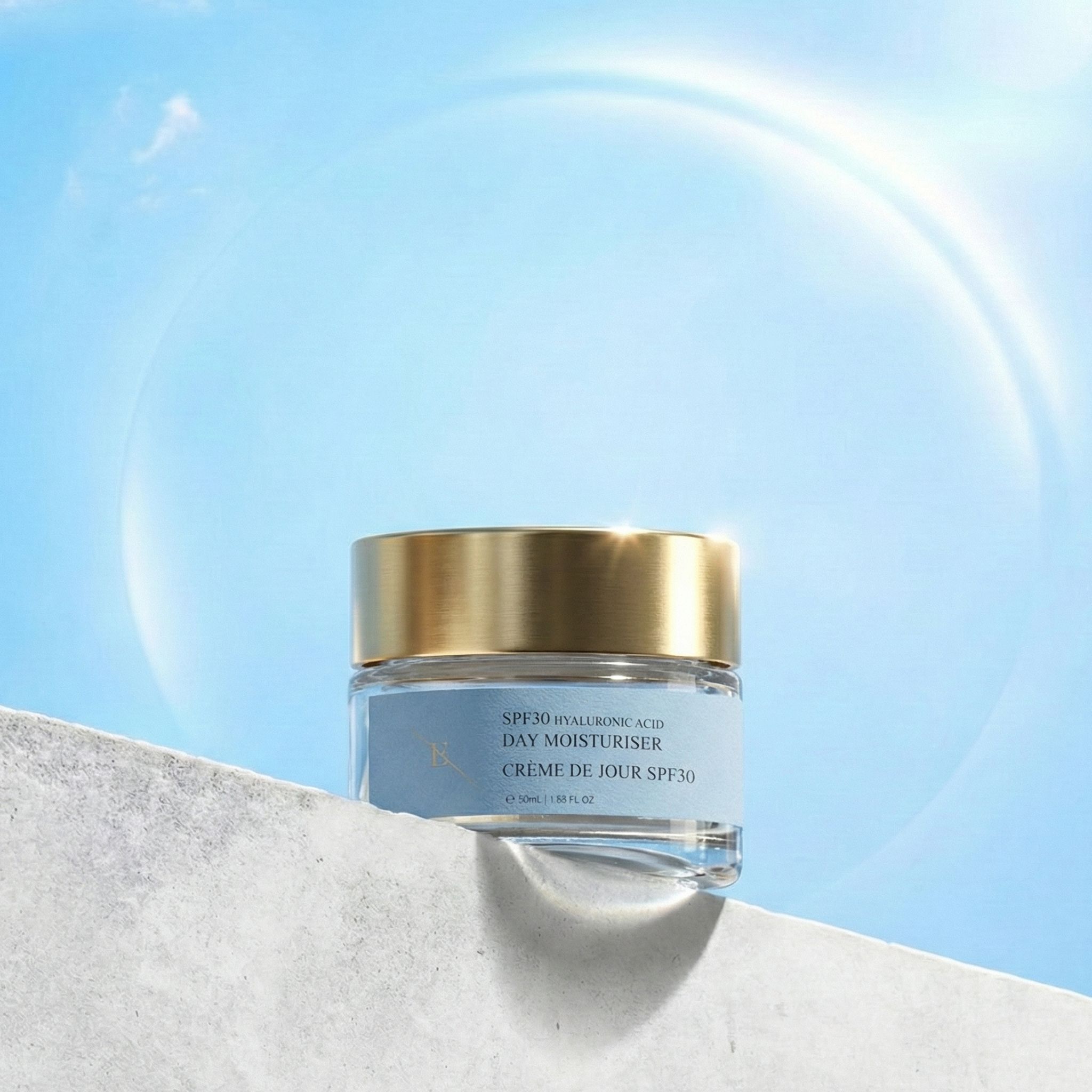 Vasetto di crema giorno con coperchio dorato davanti a cielo blu. Scritta: SPF30 Hyaluronic Acid Day Moisturiser, Crème de Jour SPF30.