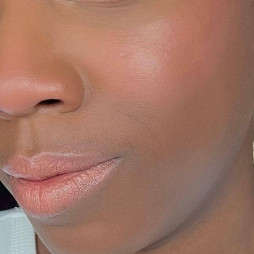 Primo piano di un viso. Labbra e guance truccate. Pelle scura.