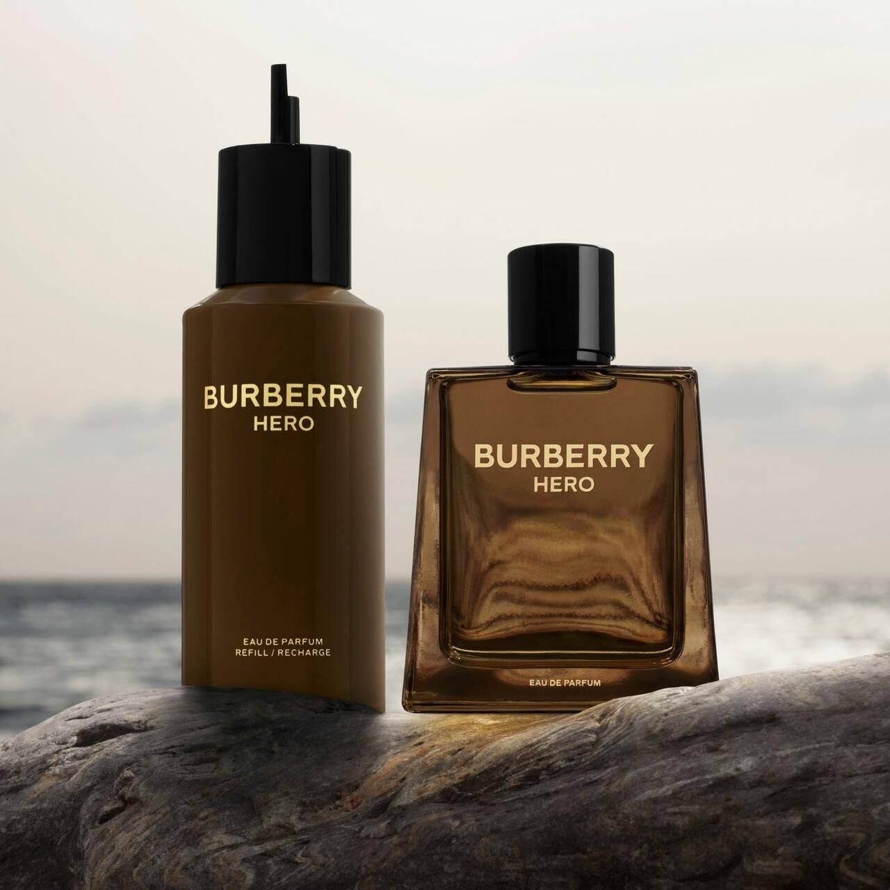 Burberry Hero Parfum e ricarica. Flaconi marroni con tappi neri. Scritta dorata. Su pietra.