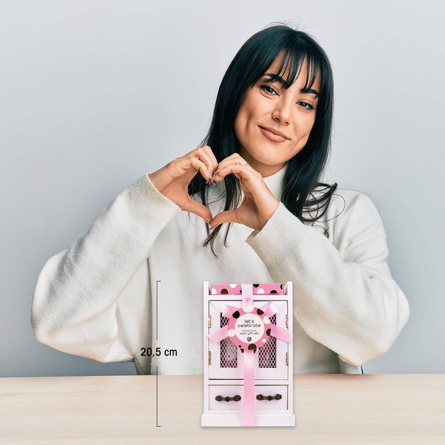 Una donna tiene in mano un set regalo a forma di cuore. Il set è alto 20,5 cm. Il set è confezionato in un armadio.