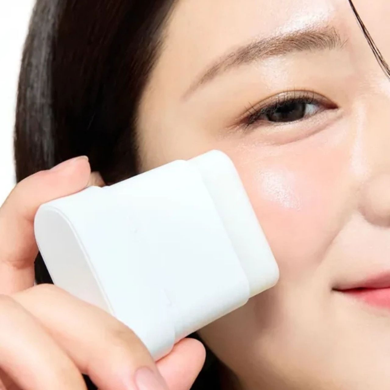 Una donna applica il SOME BY MI PDRN Spirulina Poreless Primer sulla guancia con un applicatore bianco.