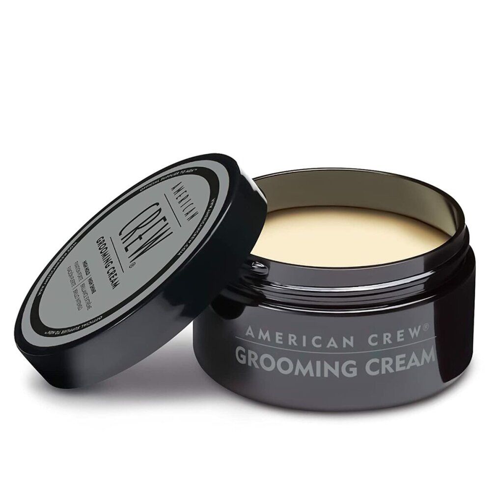 Vasetto nero con coperchio aperto. "American Crew Grooming Cream" sul coperchio e sul vasetto. Crema visibile.